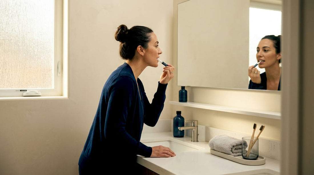 Woman applying teeth whitening pen in bathroom