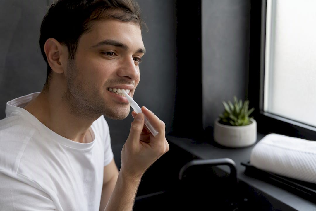 Hands applying whitening gel on teeth