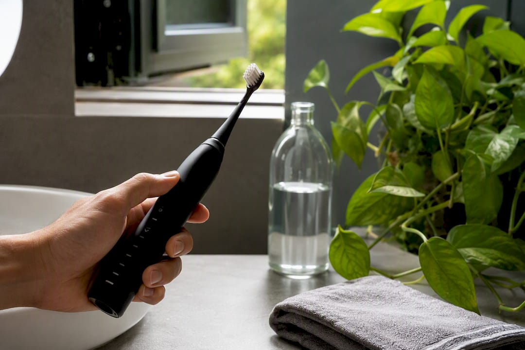Hand holding electric toothbrush with soft bristles