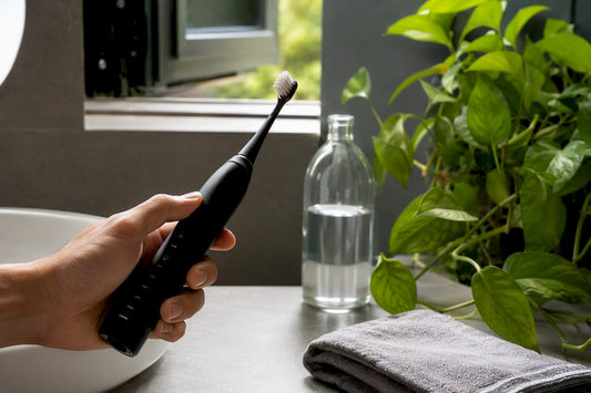 Hand holding electric toothbrush with soft bristles