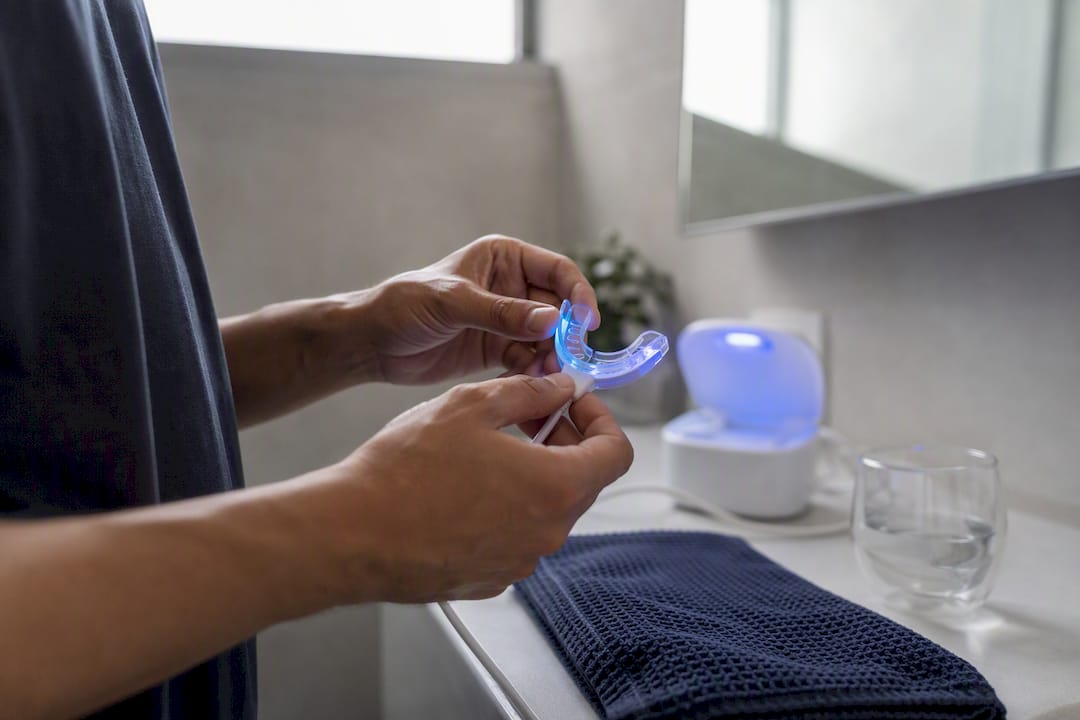 Hands holding teeth whitening tray with LED light