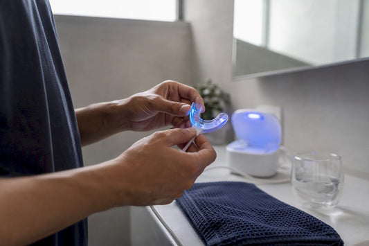 Hands holding teeth whitening tray with LED light