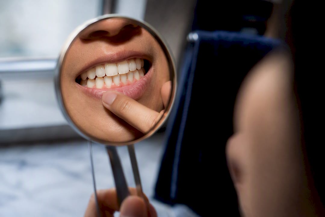 Fingertip checking tooth surface near gumline