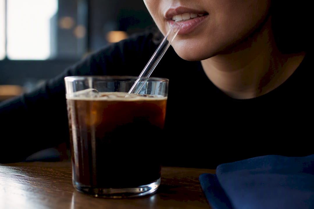 Straw directing coffee past front teeth